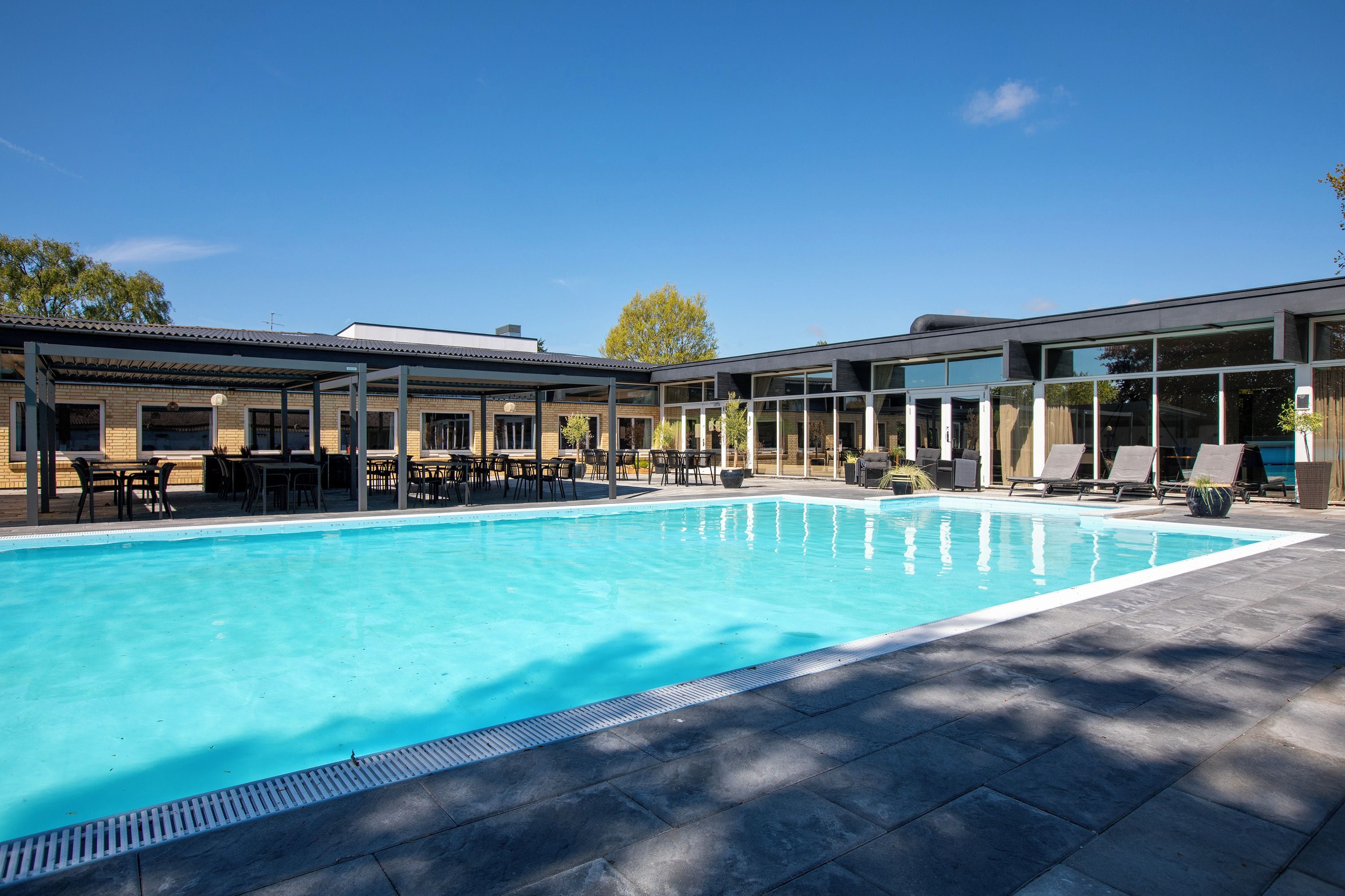 A swimming pool with a covered seating area and lounge chairs.