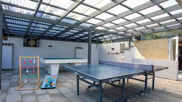 Un área recreativa al aire libre con mesa de ping pong, dardo y mesa de fútbol de mesa.
