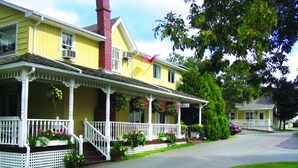 A yellow house with a white porch, a red chimney, and a flag. - Shining Waters Country Inn (Cavendish)
