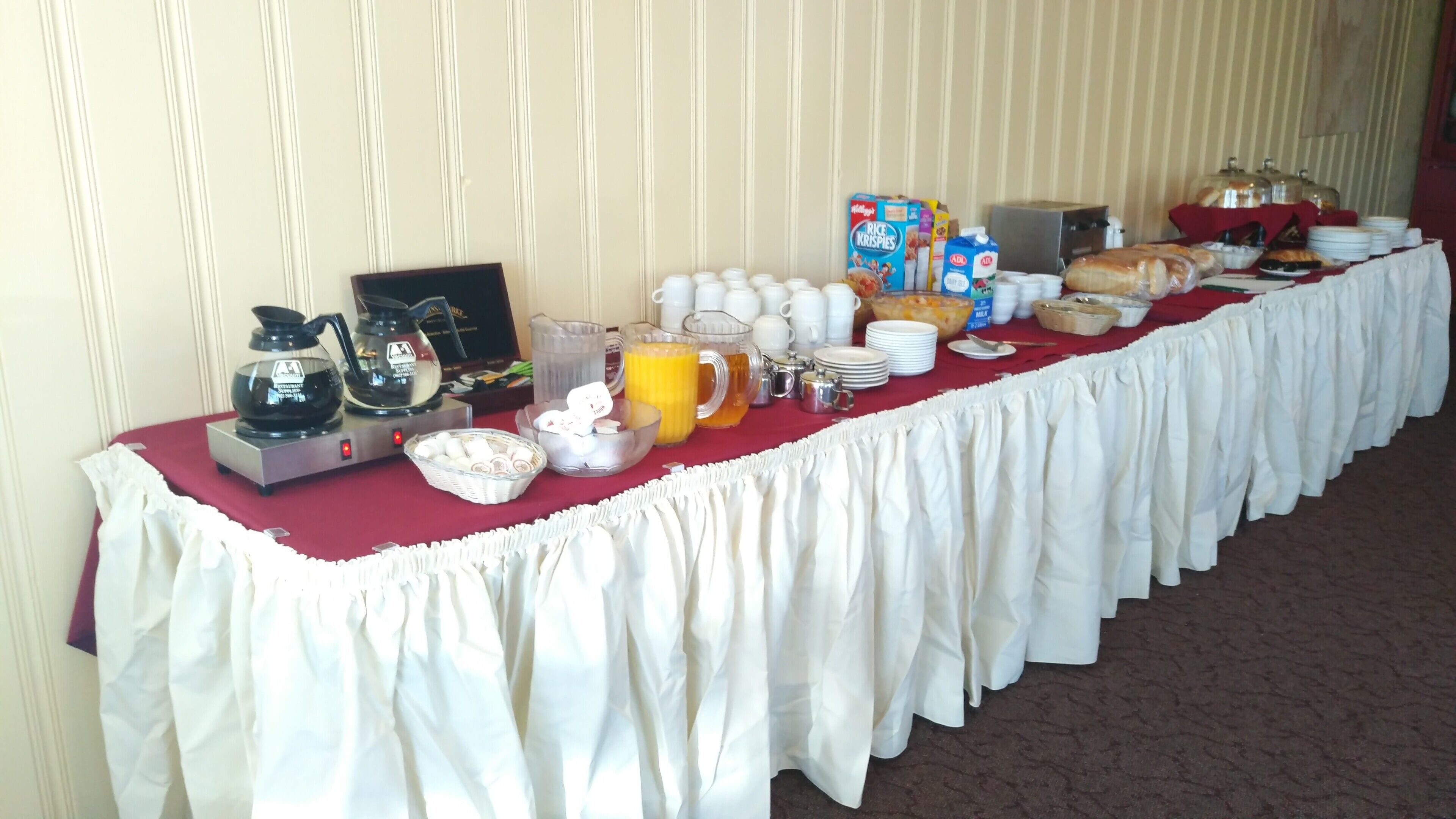 Une table de buffet proposant divers aliments et boissons, notamment des boîtes de céréales, des briques de lait et une machine à café.