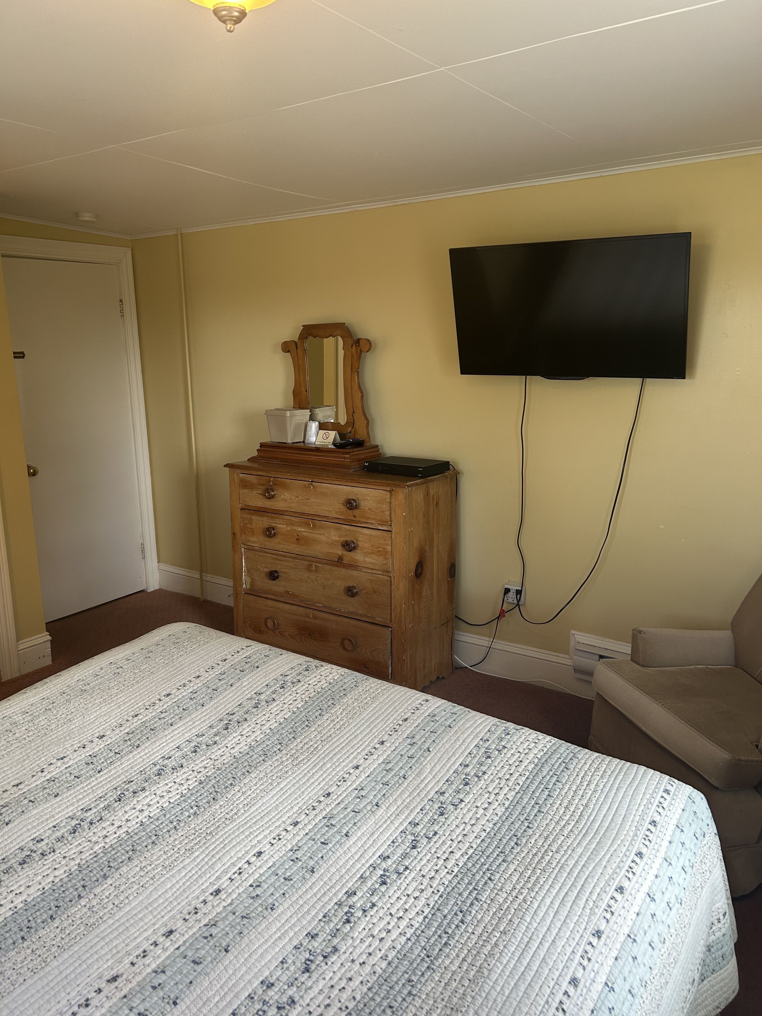 Un dormitorio con cama, cómoda, televisor y silla.