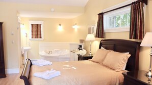 A hotel room with a bed, bedside table, lamp, and a window with curtains. - Shining Waters Country Inn (Cavendish)