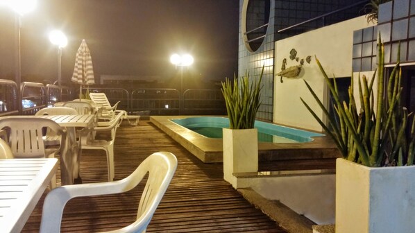An outdoor pool area with lounge chairs and a small pool.