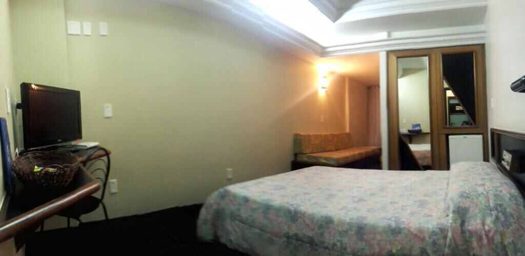 Ein Hotelzimmer mit einem Bett, einem Schreibtisch mit Computer, einem Stuhl und einem kleinen Tisch.