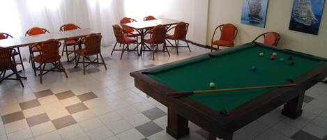 A pool table with balls, a pool table, and chairs around it.