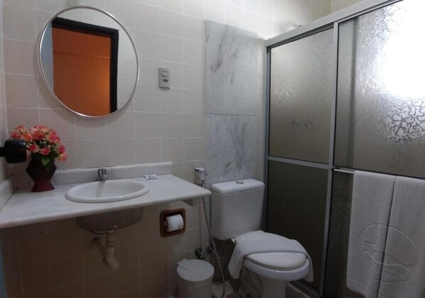 A bathroom with a white sink, mirror, toilet, and shower area.