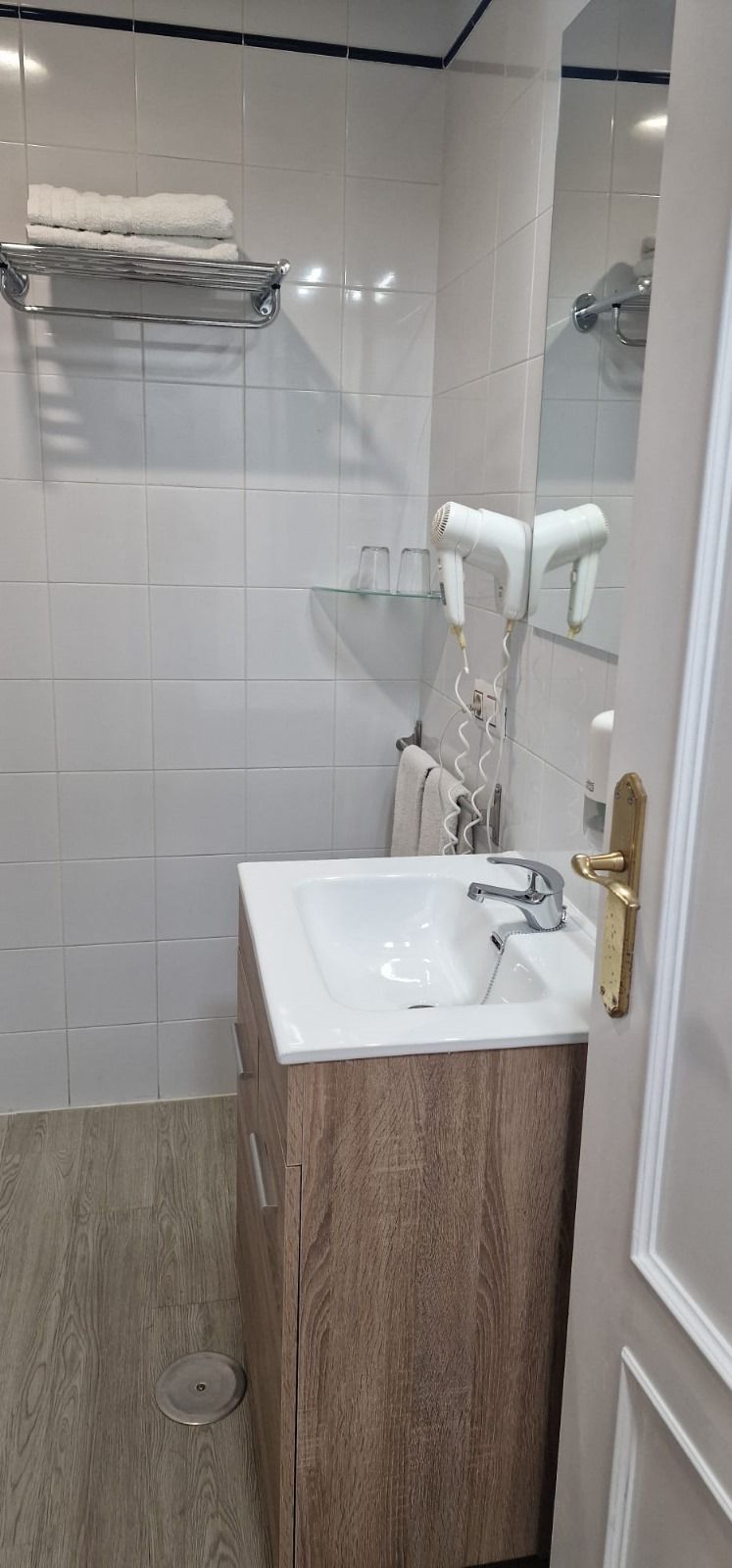Ein modernes Badezimmer mit einem weißen Waschbecken, einem Holzschrank und einem Handtuchhalter.