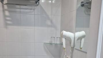 Ein modernes Badezimmer mit einem weißen Waschbecken, einem Holzschrank und einem Handtuchhalter.