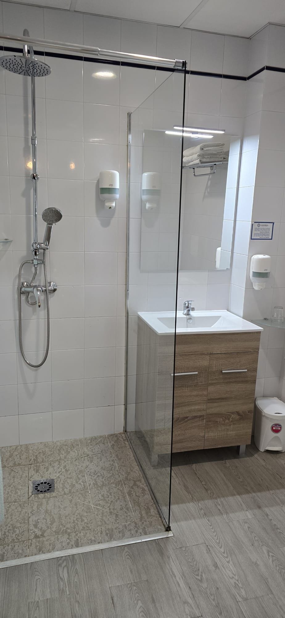 A modern bathroom with a glass-enclosed shower, a wooden vanity, and a white sink.