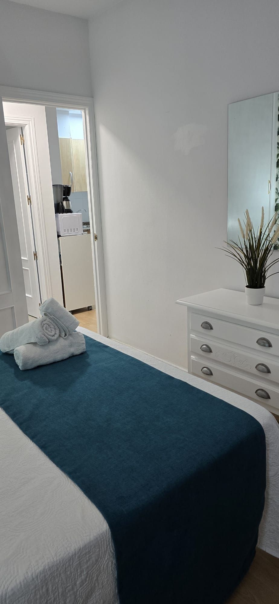 Un dormitorio con cama, cómoda, espejo y puerta que da al baño.