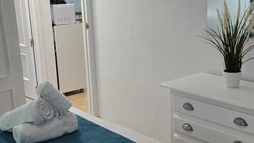 Un dormitorio con cama, cómoda, espejo y puerta que da al baño.