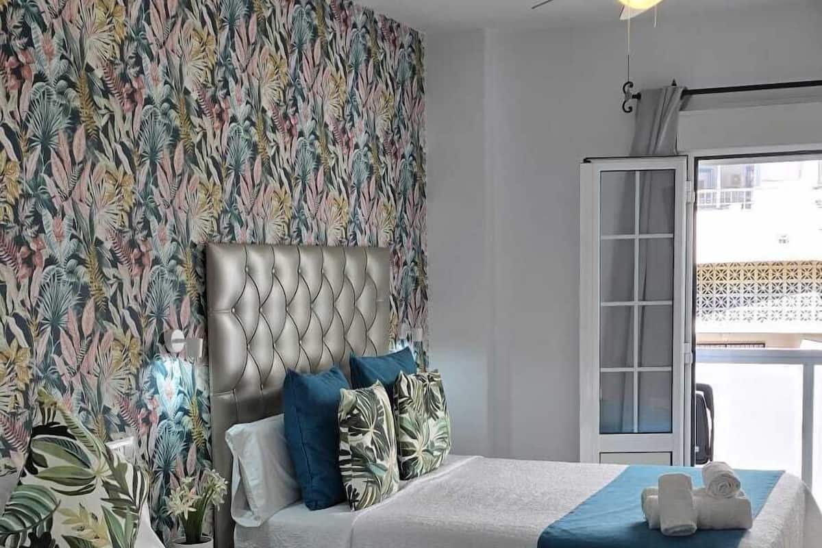 A hotel room with two beds, a ceiling fan, and a view of the outside.