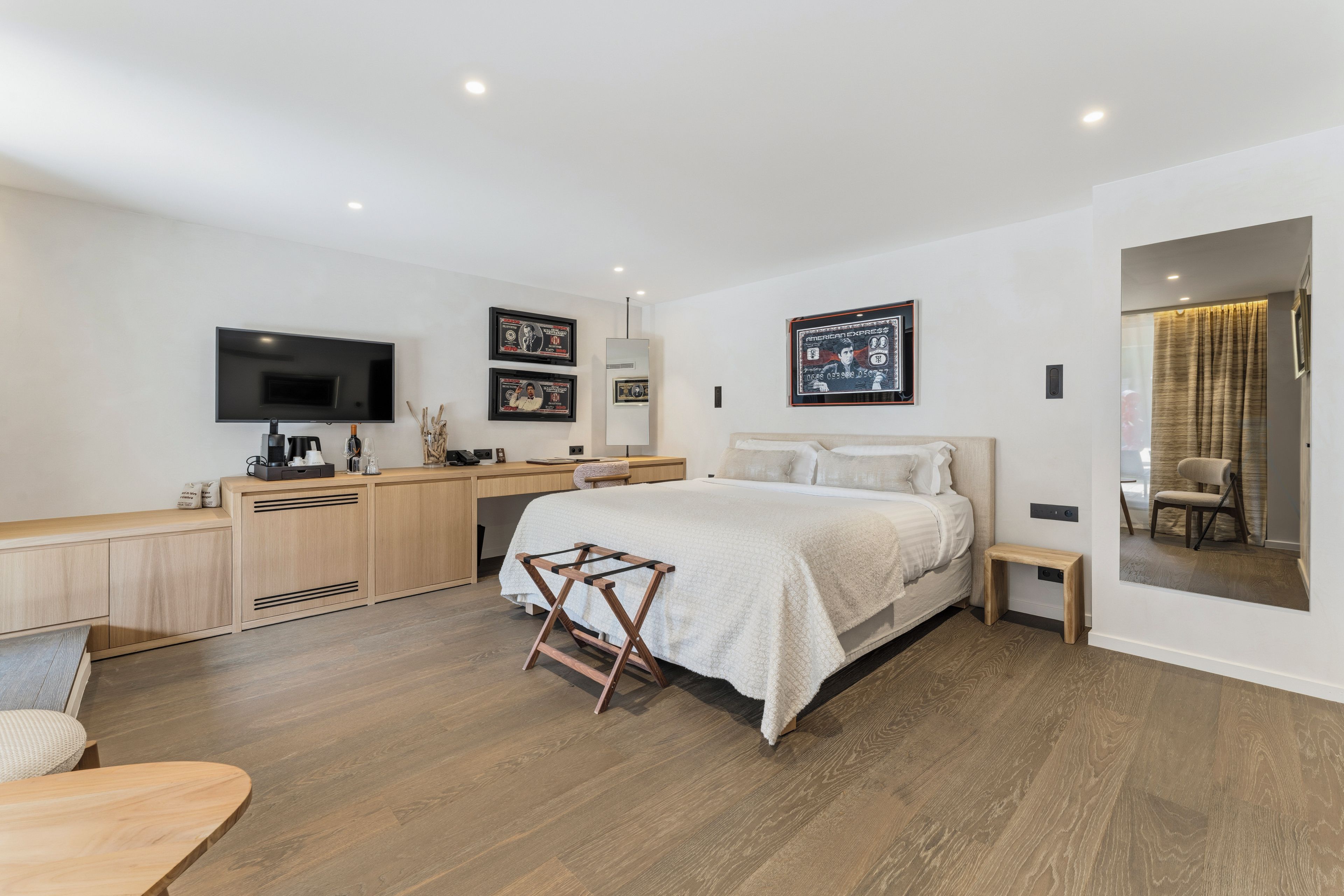 Un dormitorio moderno con cama, mesita de noche y televisor montado en la pared.