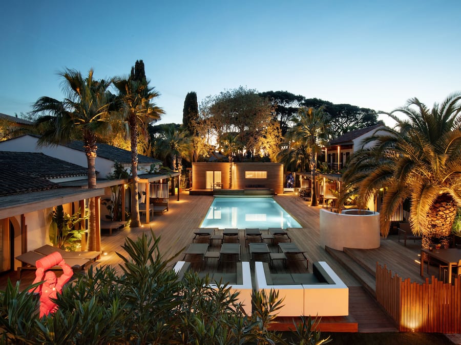 Zona de piscina con sillones de descanso, terraza de madera y vistas al paisaje circundante.