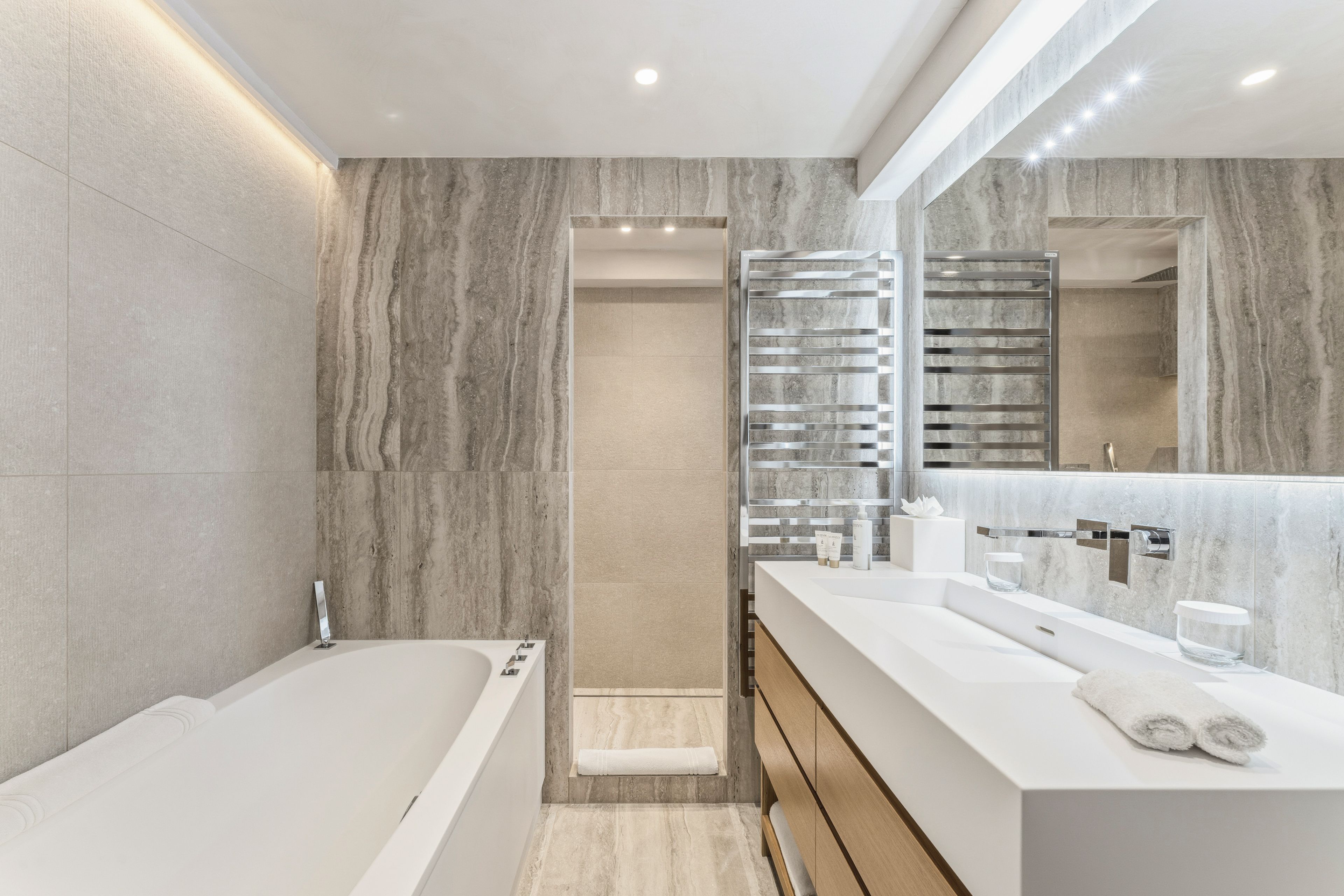 Un baño moderno con una bañera, un espejo grande y un tocador con lavabo.