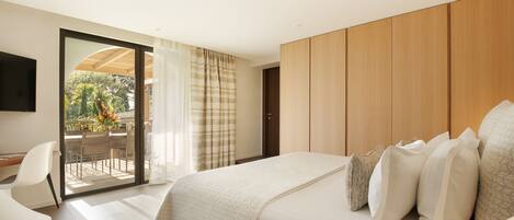 A modern bedroom with a large bed, a desk, and a sliding glass door leading to an outdoor area.
