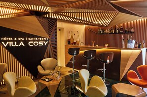 Zona de bar moderna amb panells de fusta i tamborets.