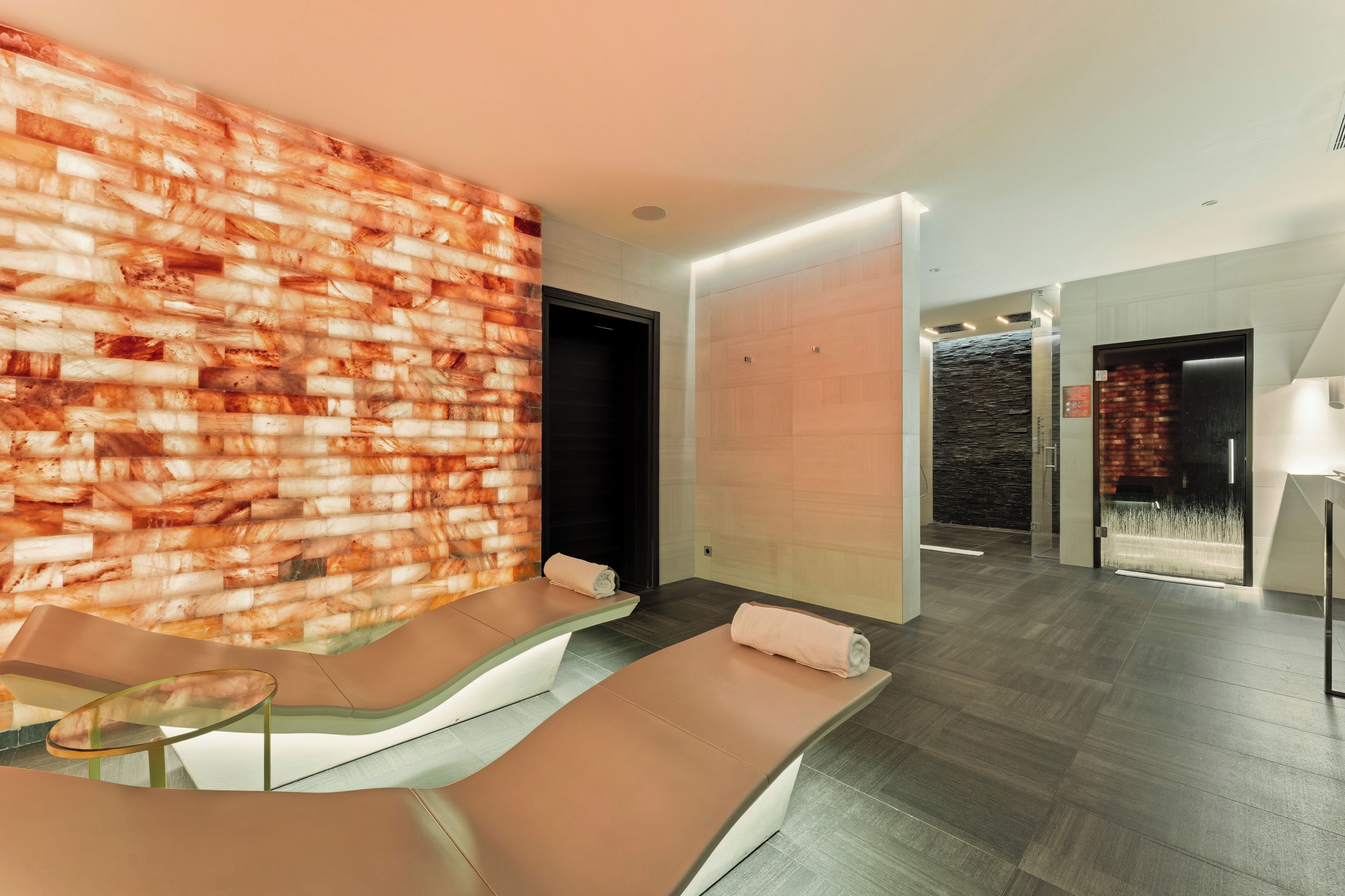 A modern spa area with a brick wall, a glass partition, and a reception desk.