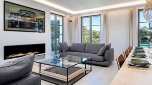 Una sala de estar moderna con una mesa de centro de vidrio, un sofá gris y una chimenea.