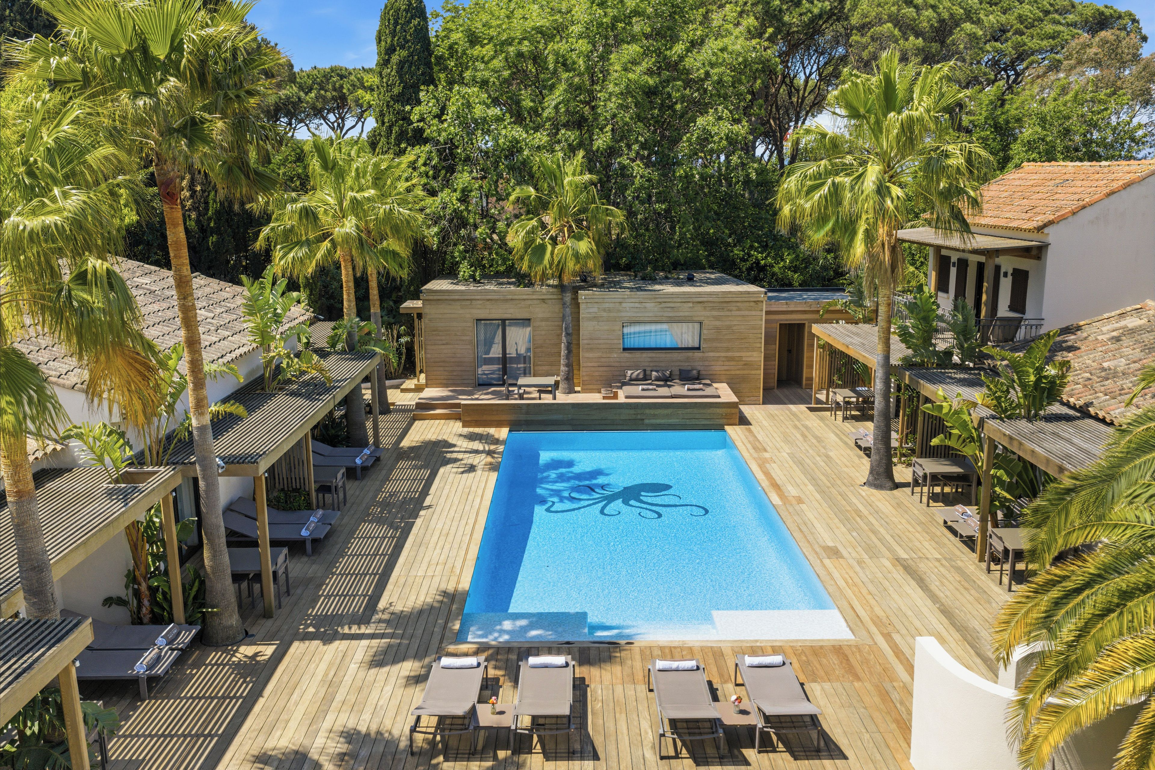 Un área de piscina con sillones de descanso y una terraza de madera.