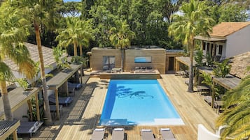 Un área de piscina con sillones de descanso y una terraza de madera.