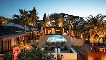 Zona de piscina con sillones de descanso, terraza de madera y vistas al paisaje circundante.