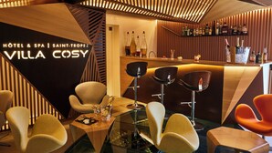 Zona de bar moderna con detalles de madera, taburetes y una variedad de botellas.