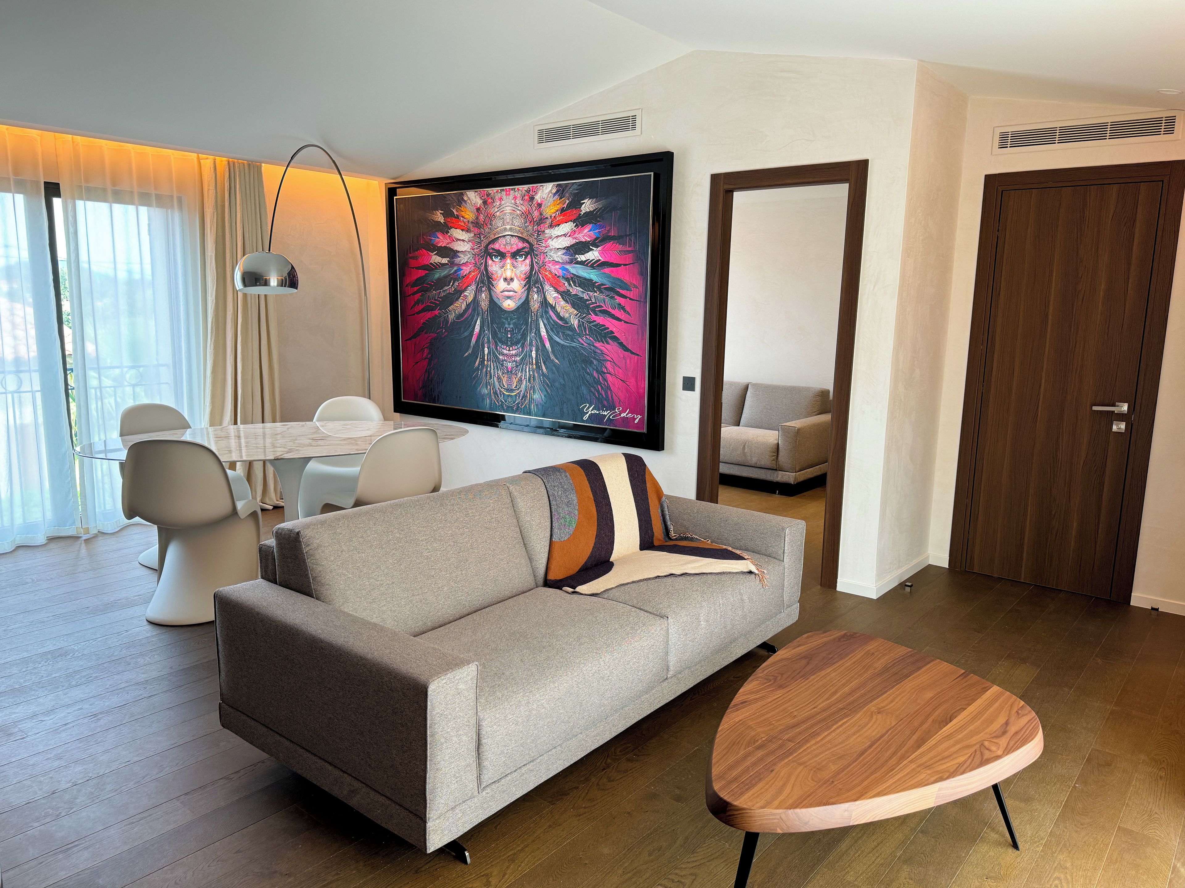 A modern living room with a sofa, coffee table, TV, and a dining area with chairs and a table.