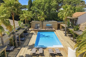 Un espace piscine avec des chaises longues et une terrasse en bois.