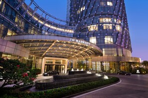 A JW Marriott hotel entrance with a curved glass facade, a landscaped garden, and a fountain. - JW Marriott Hotel Shenzhen Bao'an (Shenzhen)