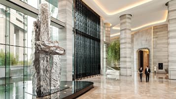 Experience the grandeur of our lobby, featuring a striking abstract sculpture, geometric patterned wall, and elegant staircase.