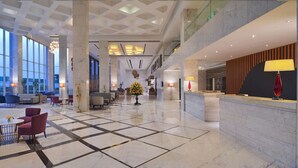A spacious lobby with a checkered floor, seating areas, and a reception desk. - Radisson Hotel Agra (Agra)