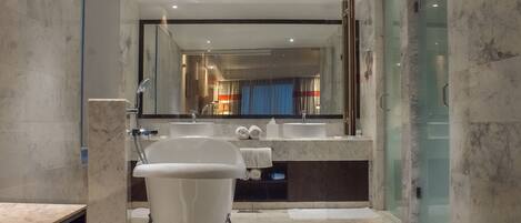 Un baño moderno con una bañera independiente, un espejo grande y una ducha con mampara de vidrio.