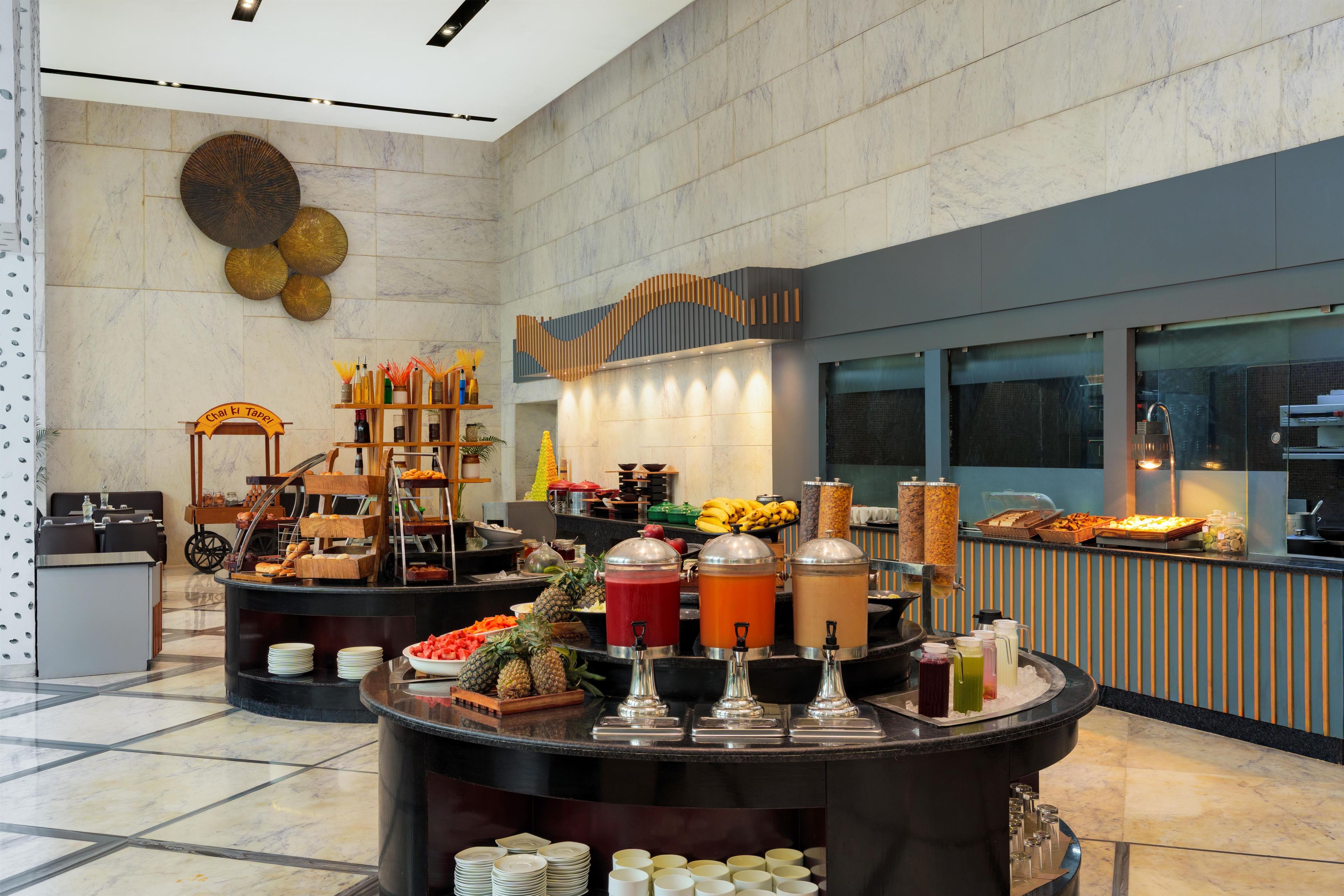 A buffet area with various food items and beverages, a reception desk, and a wall with decorative elements.