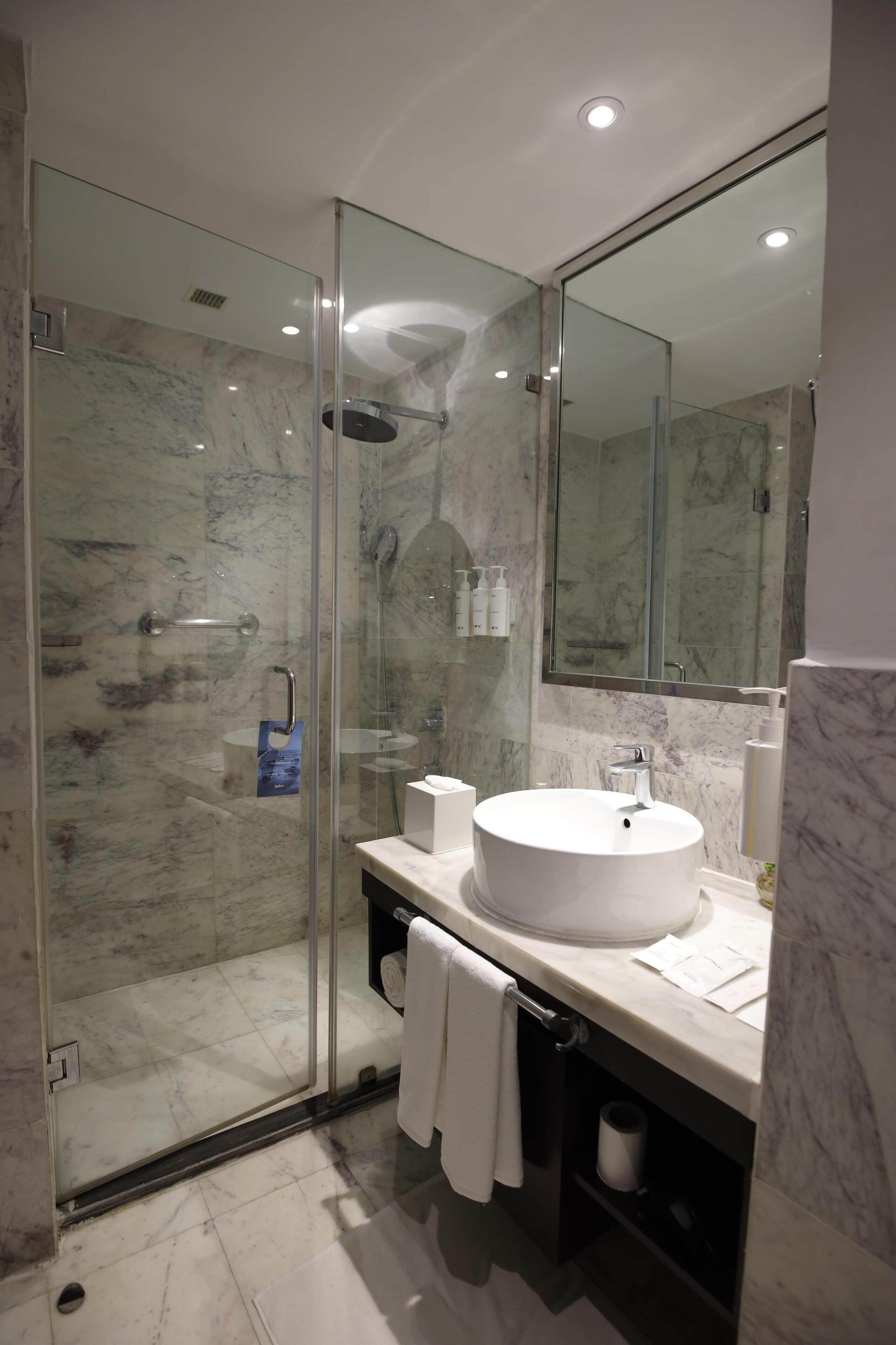 A modern bathroom with a glass-enclosed shower, a white sink, and a large mirror.