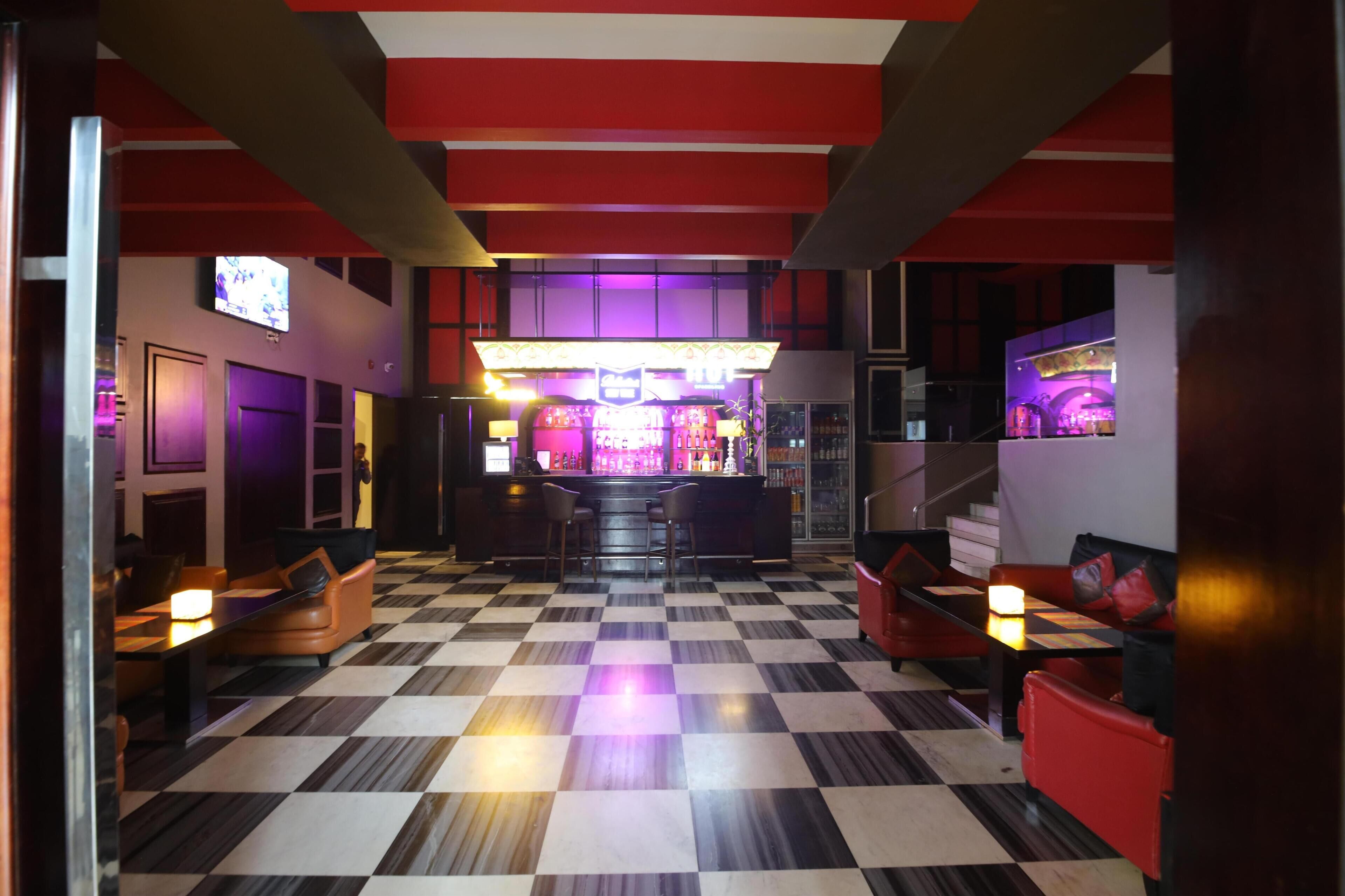 A bar area with a checkered floor, bar stools, and a counter.