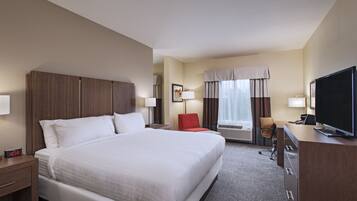 A hotel room with a large bed, a desk, a television, and a chair.