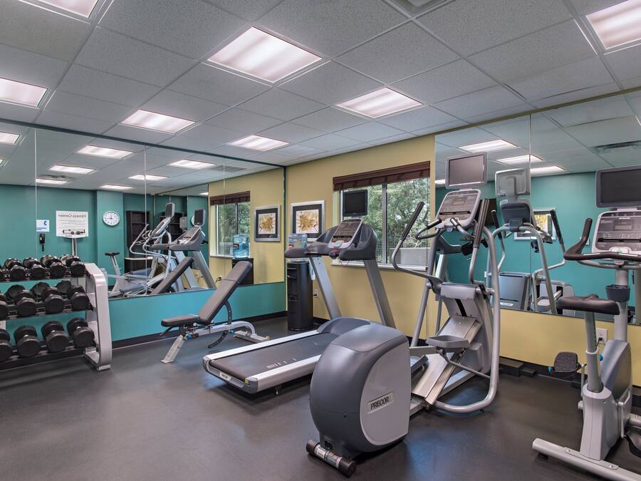 Un gimnasio con cintas de correr, elípticas y pesas libres.