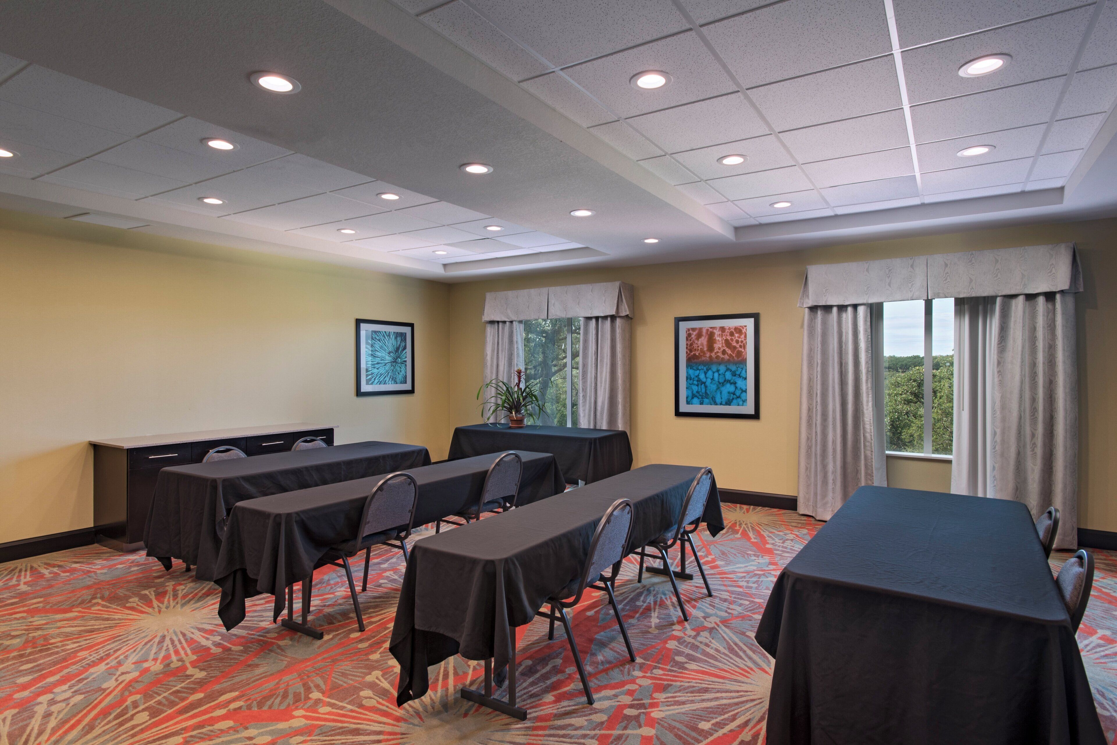 A conference room with tables, chairs, and a carpeted floor.