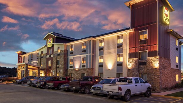 Un hotel de varios pisos con fachada de piedra, múltiples espacios de estacionamiento y un letrero que indica que es un establecimiento Marriott.