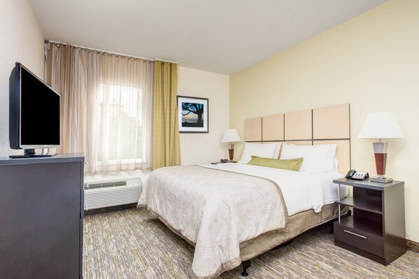 Een hotelkamer met een bed, bedlampen, een televisie, een verwarming en een schilderij aan de muur.