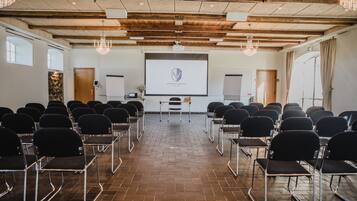 A conference room with rows of chairs, a projector screen, and a wooden ceiling.