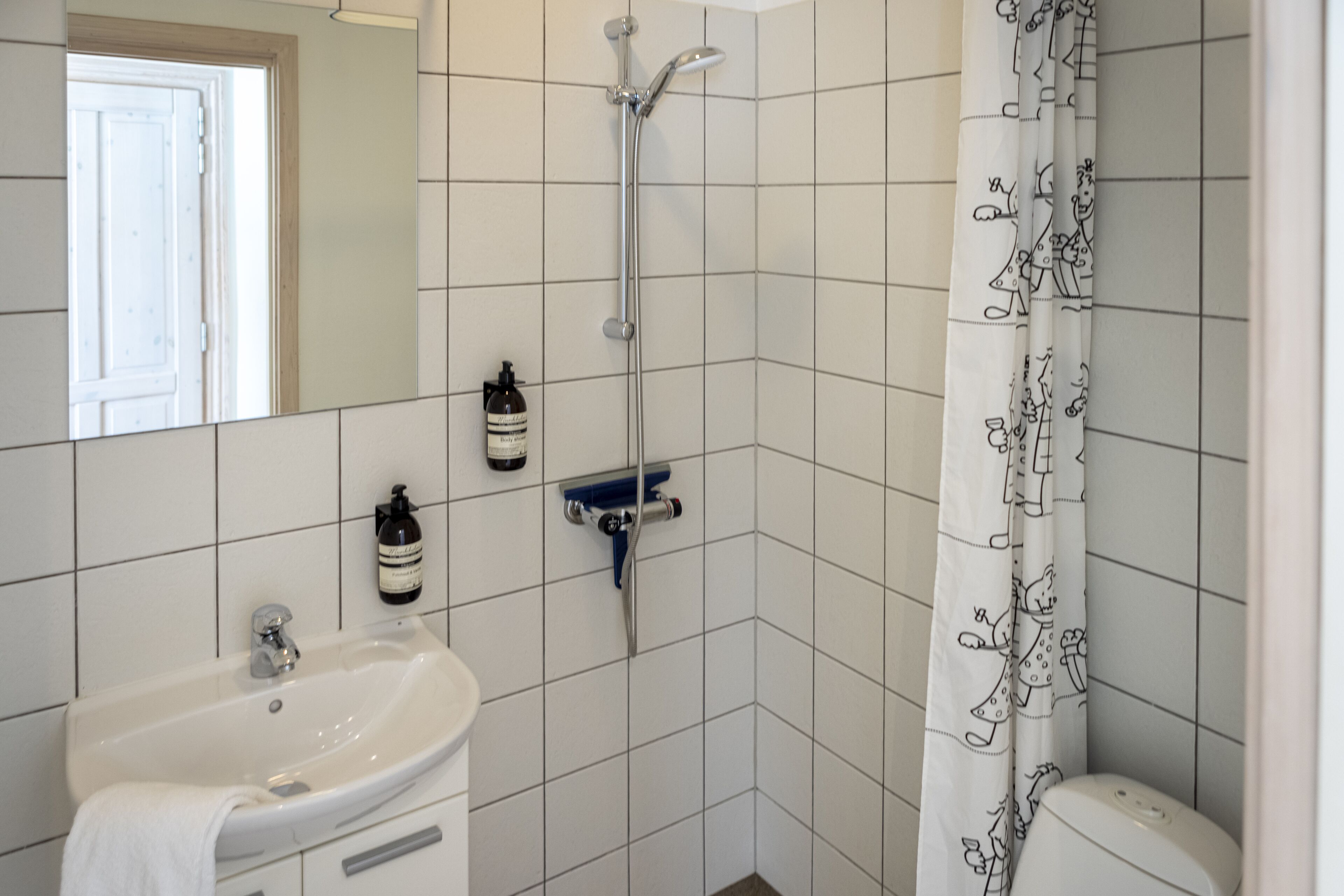 A bathroom with a white sink, a shower, and a toilet.