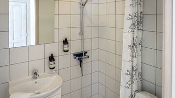 A bathroom with a white sink, a shower, and a toilet.