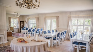 A dining area with round tables, blue chairs, and a chandelier. - Sonnerupgaard Gods (Hvalso)