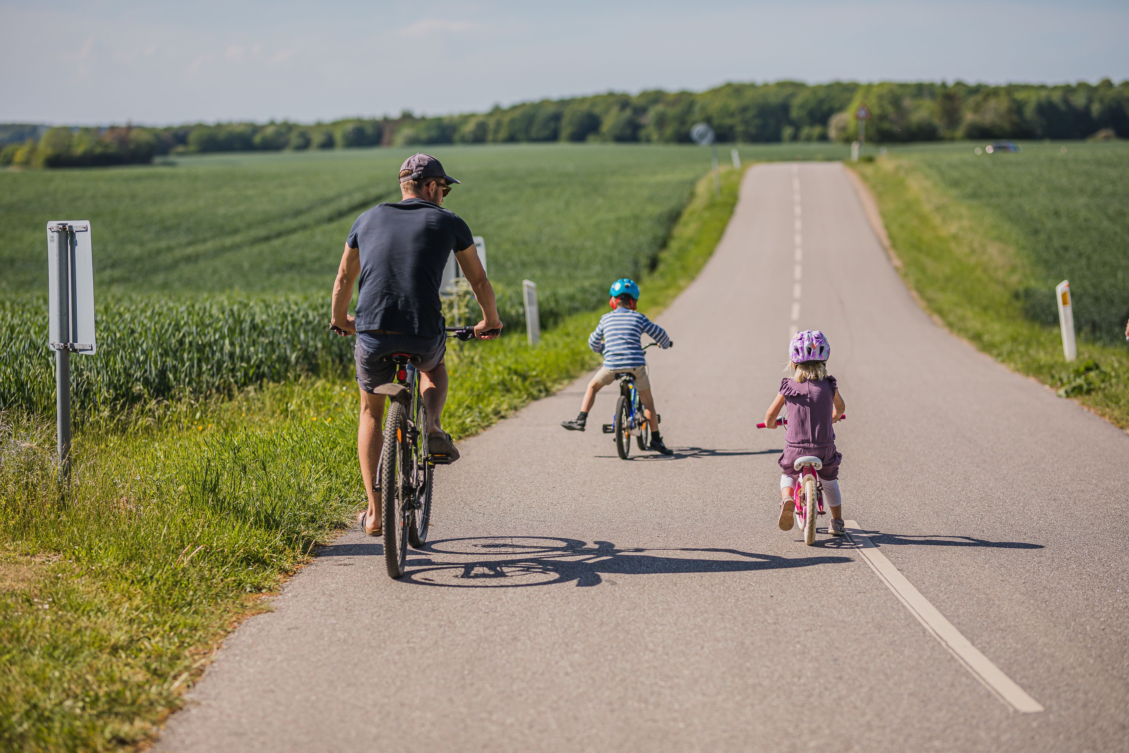 A paved path with cyclists and a cyclist with a child.