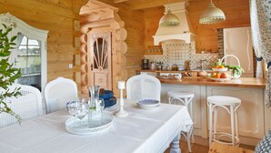 Una cabaña acogedora de madera con comedor que incluye una mesa blanca dispuesta con platos, vasos y un florero.