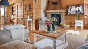 Una sala de estar acogedora con chimenea, paredes de madera, un sofá, una mesa de centro y un televisor.