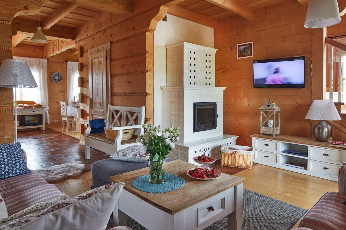 Un acogedor interior de cabaña de madera con chimenea, televisor y zona de comedor.