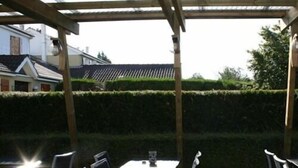 An outdoor patio area with a table and chairs, surrounded by a wooden pergola and a hedge. - Storia Da Ennio (La Verriere)